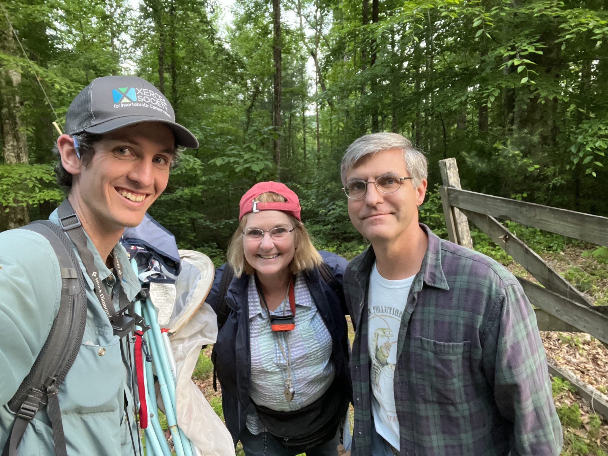Three smiling people, some with insect nets and headlamps.